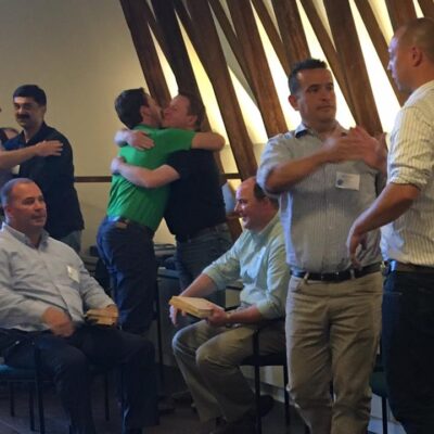 Participants celebrate with handshakes and hugs after successfully breaking boards in a team building activity focused on overcoming challenges and personal barriers. thumbnail