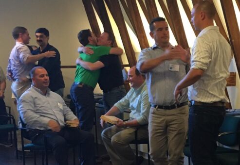 Participants celebrate with handshakes and hugs after successfully breaking boards in a team building activity focused on overcoming challenges and personal barriers.