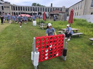 Participants are engaging in a large outdoor Connect Four game, a other popular activity in the "Ultimate Tailgate Challenge" team building program. This scene captures the fun and engaging nature of the team building event.