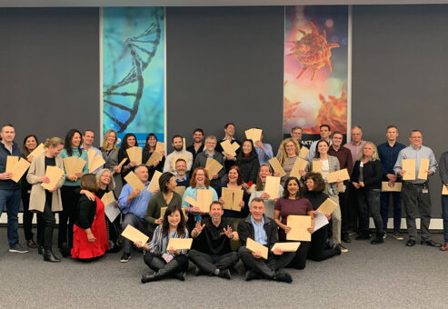 A group of participants proudly holding their broken boards after completing a team building activity focused on overcoming personal and professional barriers.