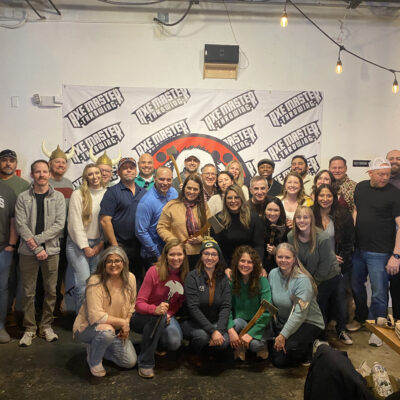 Team posing with axes after a competitive and fun axe-throwing session during a Mystery Bus team building event. thumbnail