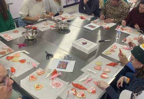 Team decorating heart-shaped cookies during a creative baking stop on the Mystery Bus team building adventure.