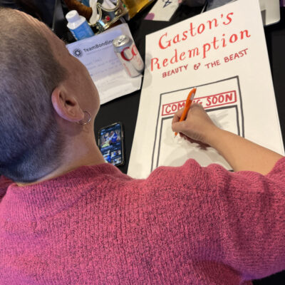 A participant draws a poster titled 'Gaston's Redemption: Beauty & The Beast' during a team building activity, showcasing creativity. thumbnail