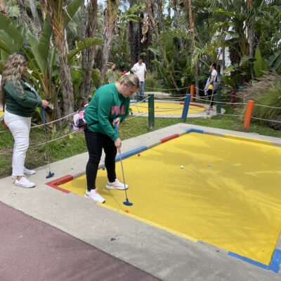 Team member enjoying a mini-golf challenge during a fun-filled stop on the Mystery Bus team building event. thumbnail