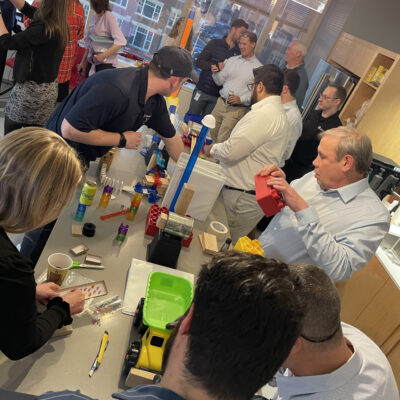 Group of participants collaborating and constructing complex devices during the Domino Effect team building event. thumbnail