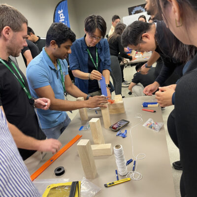 Team members working together on building a creative machine as part of the Domino Effect team building event. thumbnail