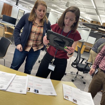 Participants analyze case files and use a tablet to uncover clues during the Corporate CSI team building activity. thumbnail