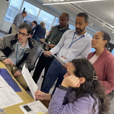 Team members collaborate by reviewing documents and discussing clues during the Corporate CSI team building exercise. thumbnail