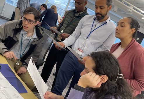 Team members collaborate by reviewing documents and discussing clues during the Corporate CSI team building exercise.