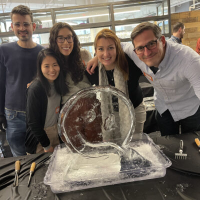A team poses proudly beside their nearly completed ice sculpture during a Team building Ice Sculpting event, demonstrating collaboration and creativity. thumbnail