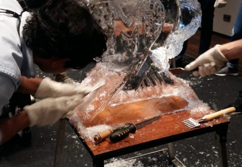 Participants work together to carve an intricate ice sculpture at a Team building Ice Sculpting event, demonstrating collaboration and creativity.