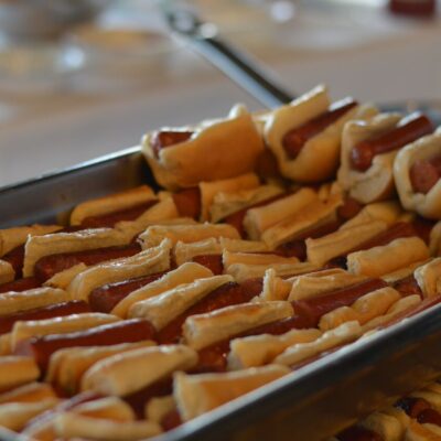 A large tray filled with mini hot dogs, each neatly placed in a small bun. The hot dogs are arranged in rows, making them easy to serve at a food truck challenge team building event. thumbnail