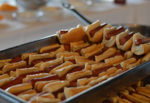 A large tray filled with mini hot dogs, each neatly placed in a small bun. The hot dogs are arranged in rows, making them easy to serve at a food truck challenge team building event.