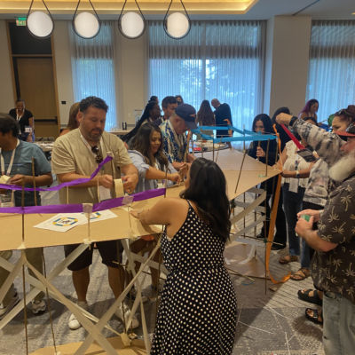 articipants in the Bridging the Divide team building activity work together to construct a large, collaborative bridge. thumbnail