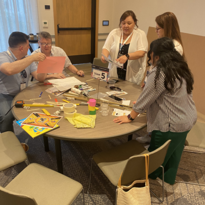 Team members work together on planning their bridge design during the Bridging the Divide team building activity. thumbnail