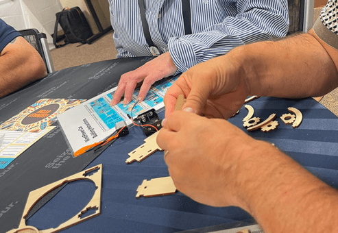 Participants assembling wooden parts of a STEM project kit during the STEM Speedway team building activity, focusing on teamwork, attention to detail, and hands-on construction.